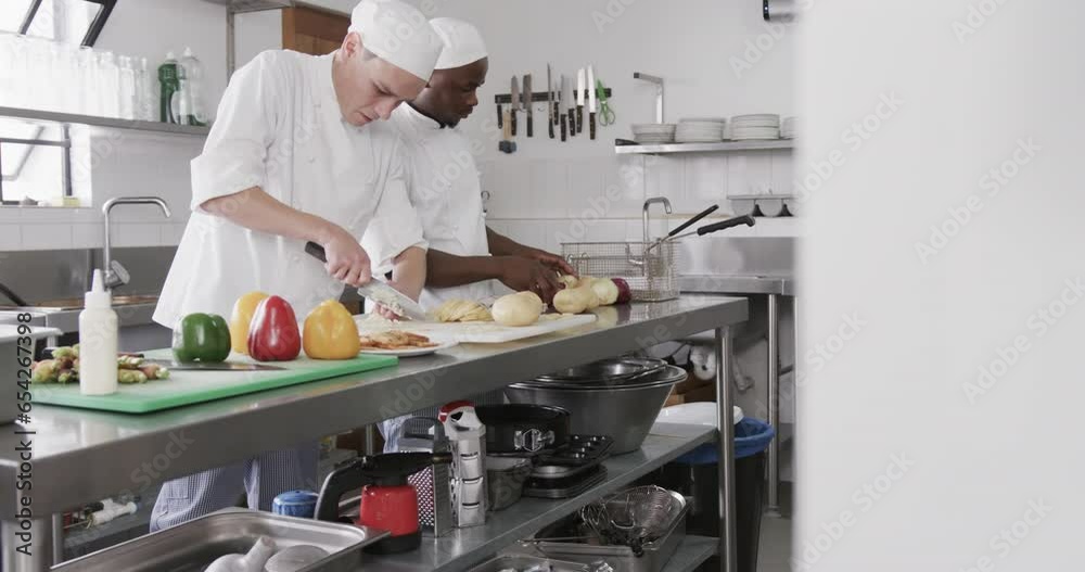 Two diverse male chefs cutting vegetables in kitchen, slow motion Two diverse male chefs cutting vegetables in kitchen, slow motion