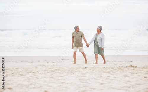Senior, couple and hand holding on the beach for retirement vacation, holiday or adventure in summer. Elderly, man and woman for walking by ocean or sea with journey and happiness for relax and love