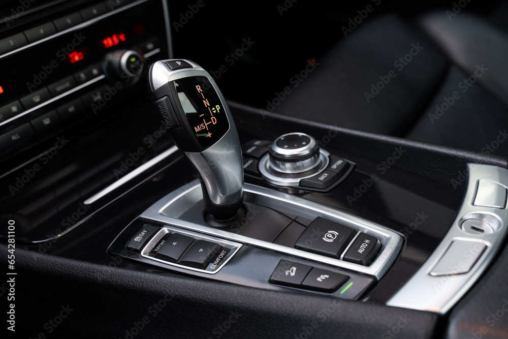 Automatic gearbox handle, multimedia dashboard and leather interior of high-end modern car. Close up of deluxe vehicle attributes.