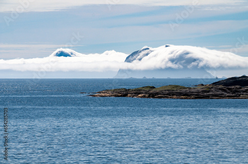 The coast of Lofoten island in Norway with rocks shrouded in clouds low above sea level.