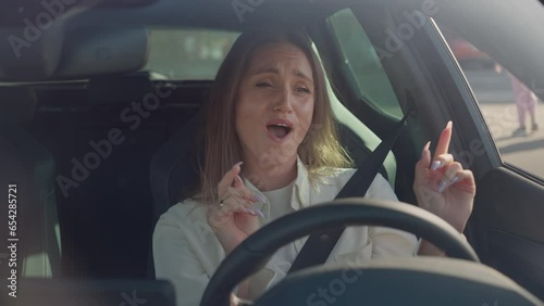 Woman listening and singing song while driving modern car