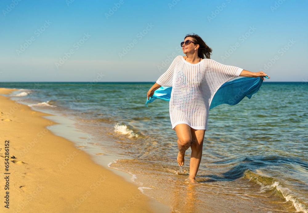 Happy beautiful woman holding shawl walking on sunny beach
Happy beautiful woman holding shawl walking on sunny beach