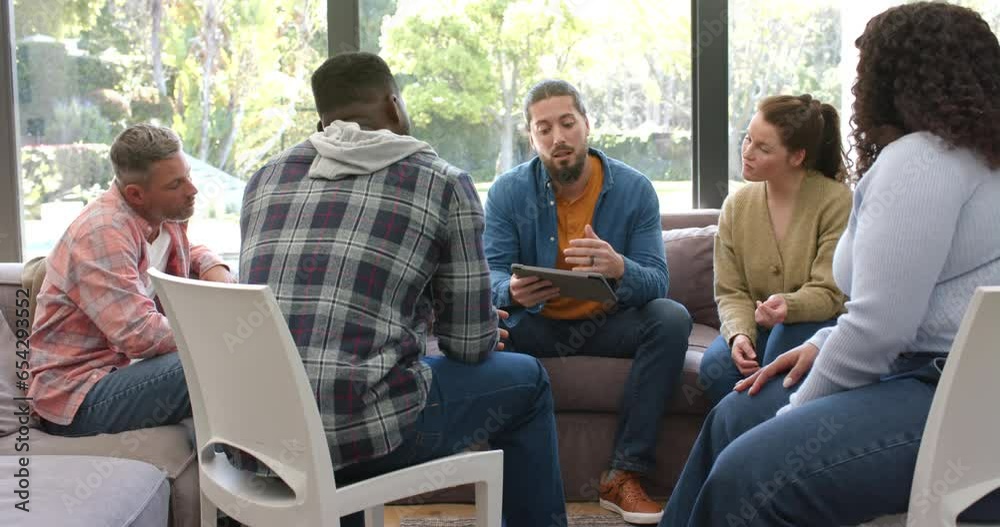 Diverse group of friends and male therapist with tablet in group therapy session
