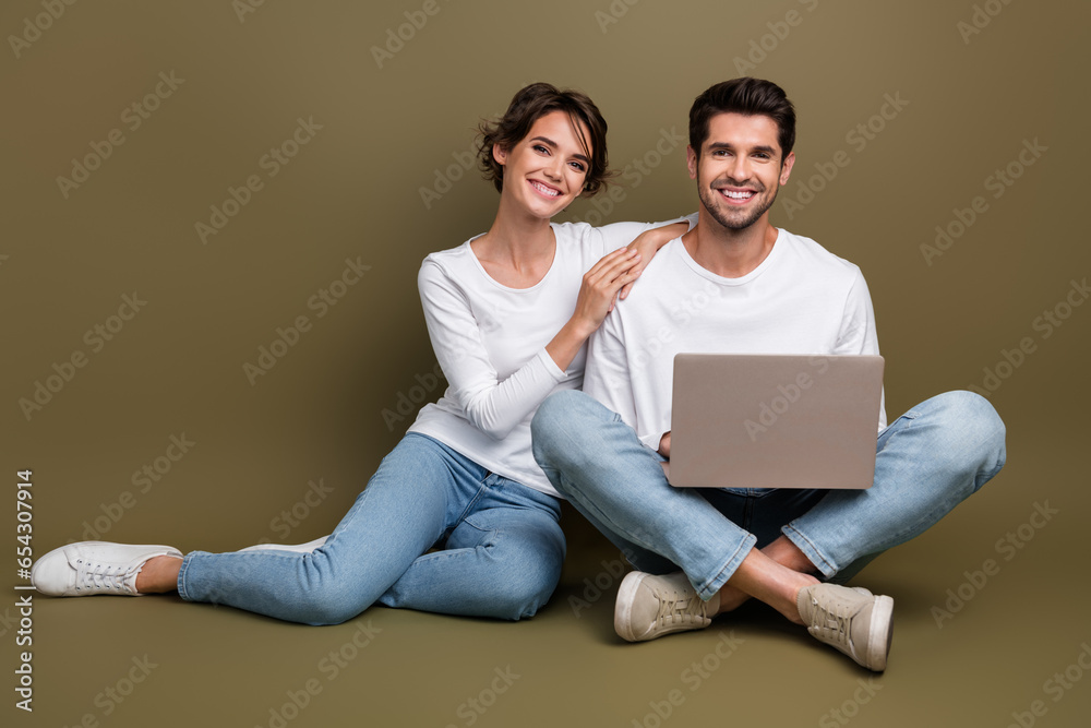 Full length photo of cute pretty married couple wear white shirts typing modern gadget empty space isolated brown color background Full length photo of cute pretty married couple wear white shirts typing modern gadget empty space isolated brown color background