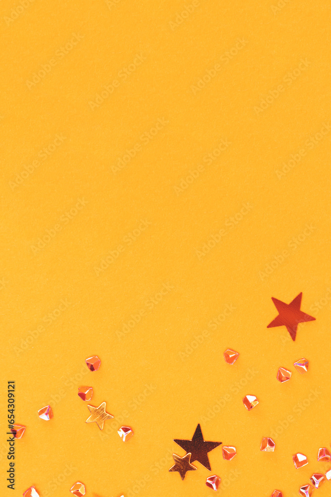 Golden stars and crystals confetti scattered on a yellow background. Shiny creative concept.