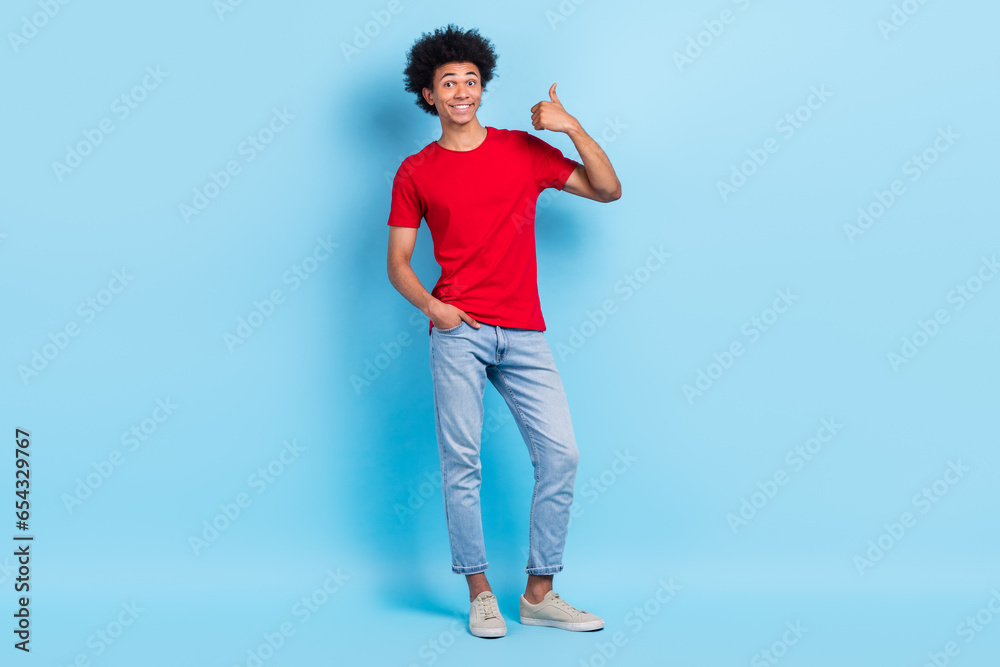 Full length photo of optimistic satisfied person wear red t-shirt denim trousers show thumb up good job isolated on blue color background Full length photo of optimistic satisfied person wear red t-shirt denim trousers show thumb up good job isolated on blue color background
