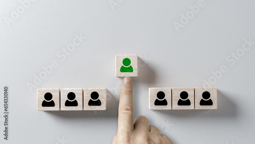 choosing right person. hand selects cube with person highlighted in green. Human resources management and recruitment business hiring concept, corporate hierarchy, recruiter chooses one leader person
