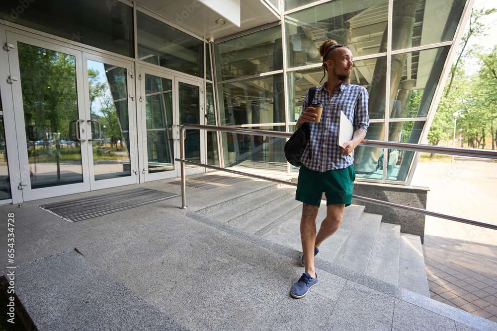 Freelancer stands at the entrance to a modern office building