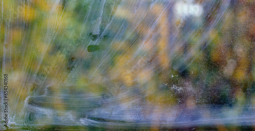 Dirty window glass with straps and sports against an autumn nature backdrop. It's time to wash the windows.