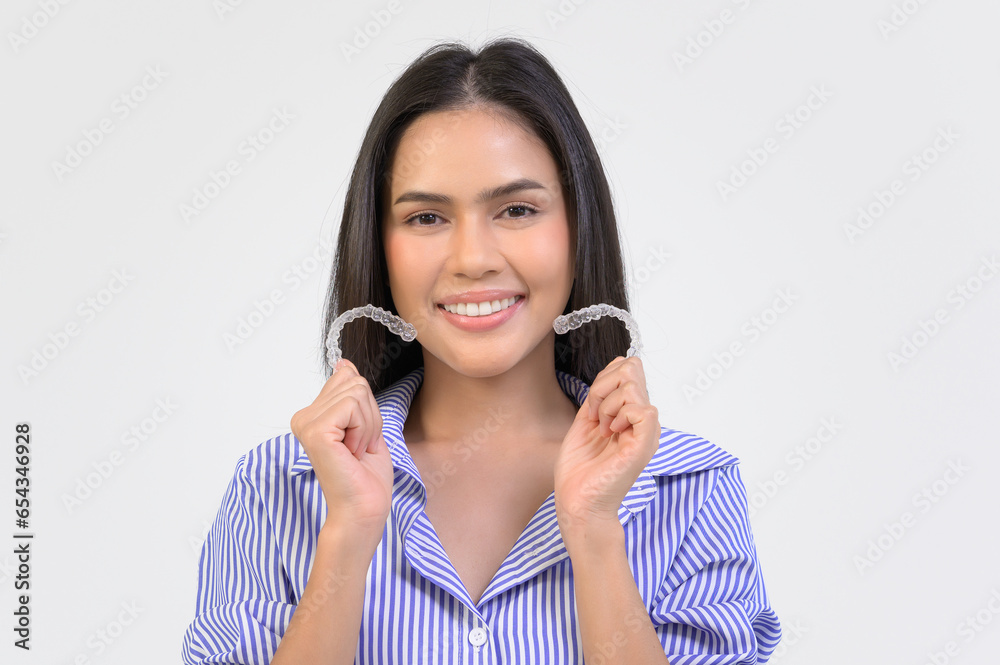 Young smiling woman holding invisalign braces over white background studio, dental healthcare and Orthodontic concept.. Young smiling woman holding invisalign braces over white background studio, dental healthcare and Orthodontic concept..