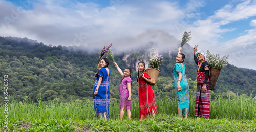 Tableau sur toile A group of women dressed in a Karen costume picks flowers and puts them in basket in mountains background