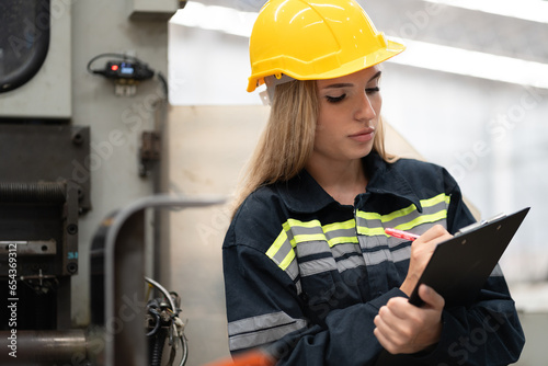 Beautiful Caucasian engineer woman working or checking machine at factory 