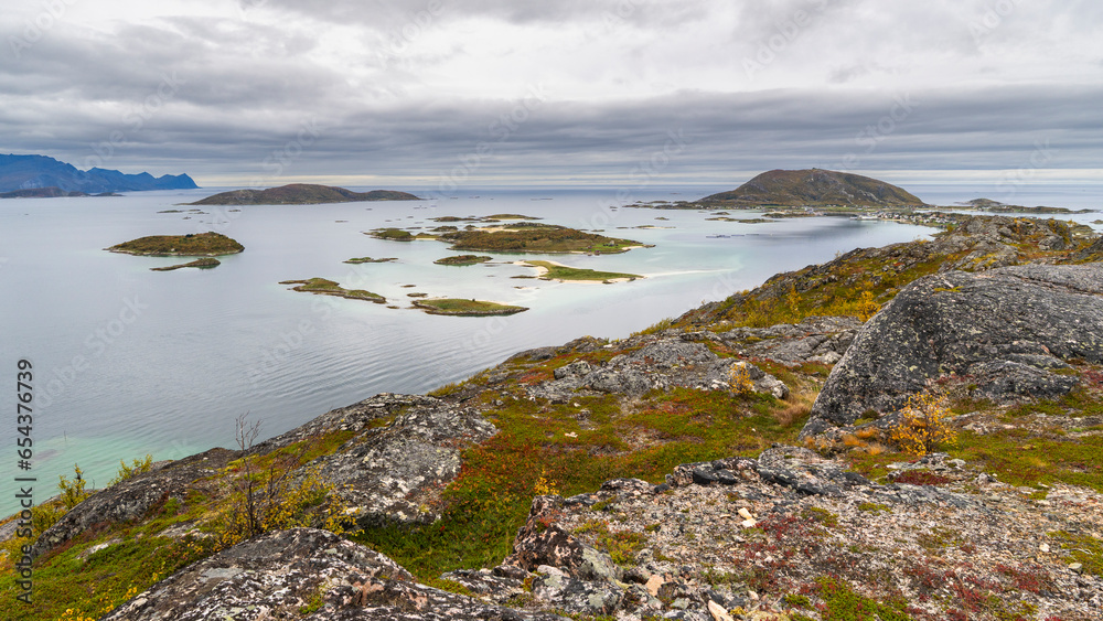 Blick über die Inseln von Sommarøy und Hillesøy mit Häuser, Brücke, Felsen, Wiesen und Strand, Ufer und Berg, Frau auf dem Berg in Norwegen. Panorama am sonnigen Herbsttag Blick über die Inseln von Sommarøy und Hillesøy mit Häuser, Brücke, Felsen, Wiesen und Strand, Ufer und Berg, Frau auf dem Berg in Norwegen. Panorama am sonnigen Herbsttag