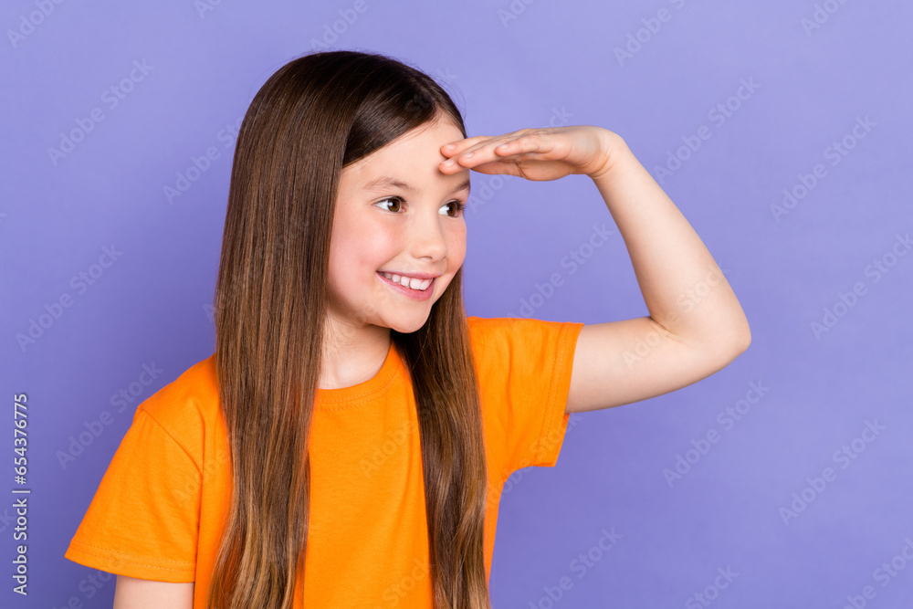 Photo of nice schoolkid with straight hairdo dressed orange t-shirt arm on forehead look empty space isolated on purple color background