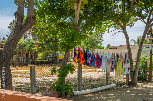 Zihuatanejo; de Azueta; Guerrero; Costa Grande; Mexico; Zihuatanejo, Mexico - July 18, 2023: Line of wet colorful laundry and bathing suits hanging between green foliage trees just off Playa Larga. Tr photo