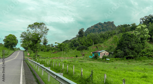 Hermoso paisaje verde con arboles y montañas que rodean casa campesina photo