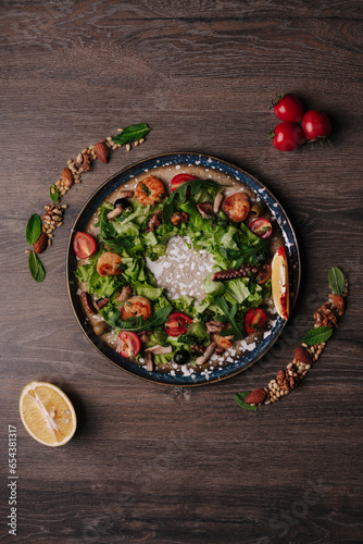 vegetable salad of arugula, moitdora and olives on a tray on a wooden table