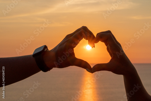 Hands heart sea sanset. Hands forming a heart shape made against the sun sky of a sunrise or sunset on a beach