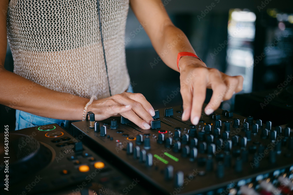 woman DJ Hands creating and regulating music on dj console mixer in a music festival woman DJ Hands creating and regulating music on dj console mixer in a music festival