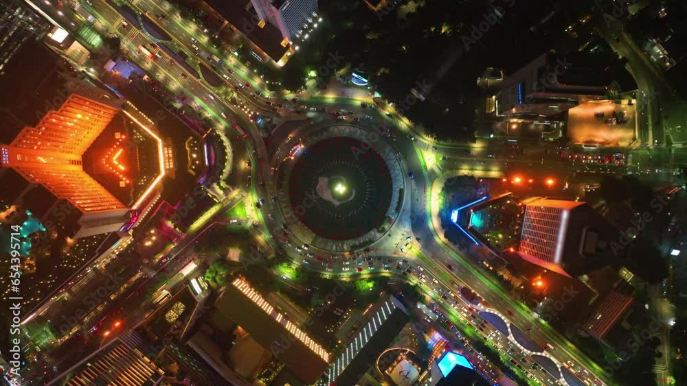 Aerial View of traffic on roundabout around Selamat Datang monument, Multi lane highway in large urban city center Cityscape of high rise buildings in Jakarta, Indonesia at night