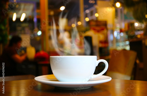 Closeup of a cup of hot coffee with rising smoke on wooden table