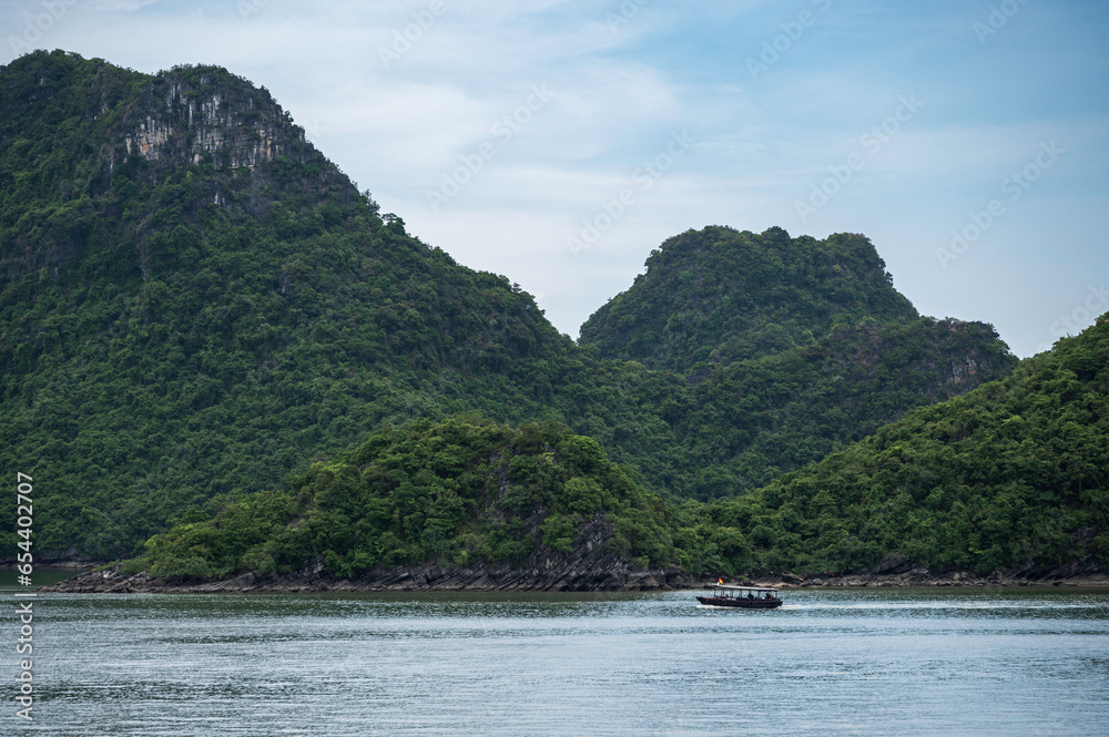 Small fishing boats, in the spectacular scenary of Ha Long Bay, Vietnam. One of the modern natural wonders of the world.
