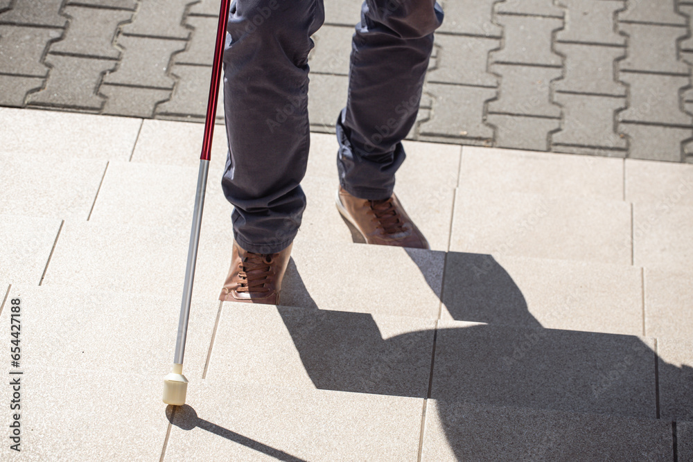 Obraz premium A blind man tries to climb the stairs, Problems of blind people, Concept, Barriers and social exclusion of people with disabilities