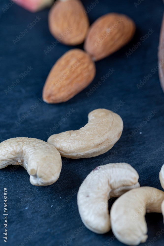 Fototapeta premium peeled cashew nuts on a black slate board, close-up