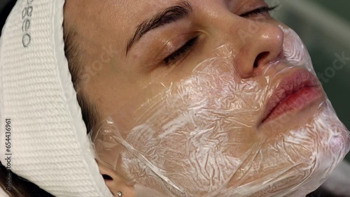 Cosmetologist applying cream with anesthesia on patient's face, portrait closeup view. Preparing skin for biorevitalization or thread lifting procedure. Woman in beauty clinic with doctor beautician.