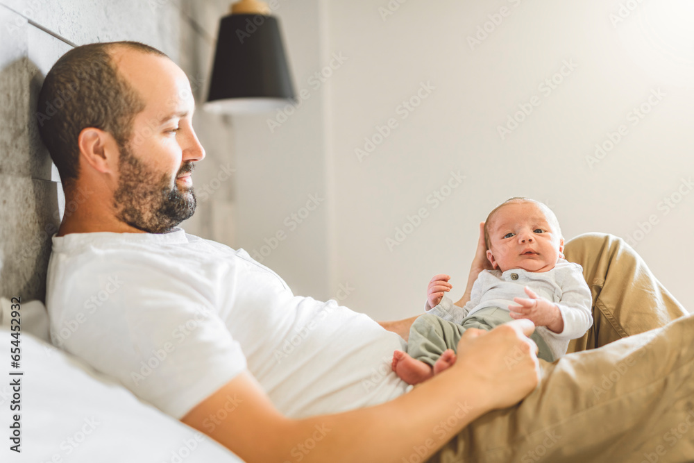 father on bedroom with his newborn baby son father on bedroom with his newborn baby son