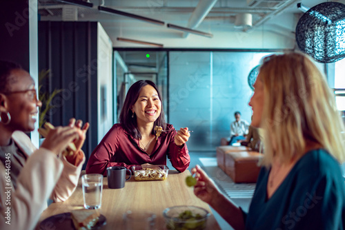 Diverse group of female coworkers having lunch together in a modern office photo