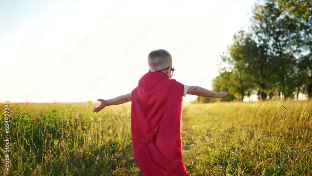 child superhero running in the park. happy family kid dream concept. a child with a red cape runs playing superhero outdoors in the park. superhero boy runs lifestyle along the path in summer child superhero running in the park. happy family kid dream concept. a child with a red cape runs playing superhero outdoors in the park. superhero boy runs lifestyle along the path in summer