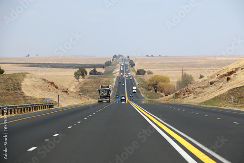 The N3 freeway from Johannesburg to Durban in South Africa, straight road to the horizon over dry landscape with cars and trucks from drivers point of view