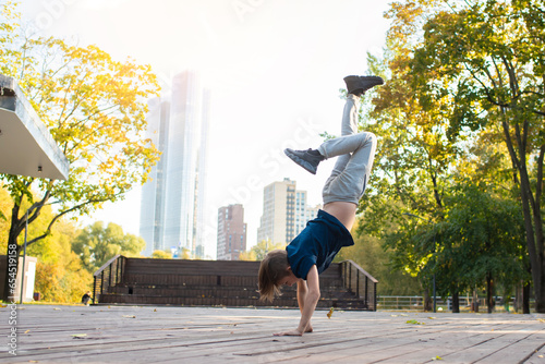 child, teenager dancing in a park in the city. An 11 year old boy is doing breakdancing outside on a sunny autumn evening.