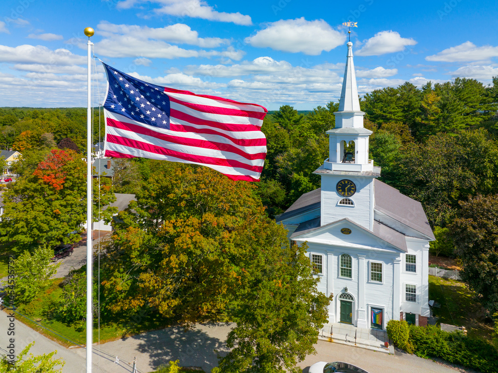 First Religious Society church aerial view at 27 School Street and US National Flag at Town Common in historic town center of Carlisle, Massachusetts MA, USA.