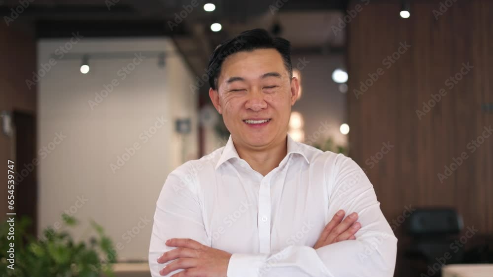 Portrait of successful office manager gazing at camera and making happy sincere smile. Cheerful employee in formal wear making arms crossed and posing on spacious contemporary workspace background.