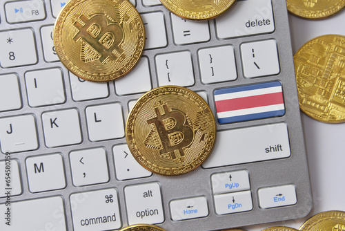 national flag of costa rica on the keyboard with bitcoin coins on a grey background. photo