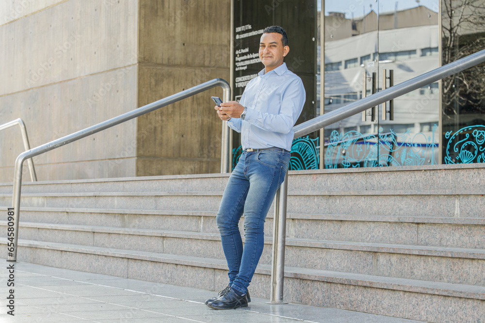 Latino man using a mobile phone on the stairs of a building. Latino man using a mobile phone on the stairs of a building.