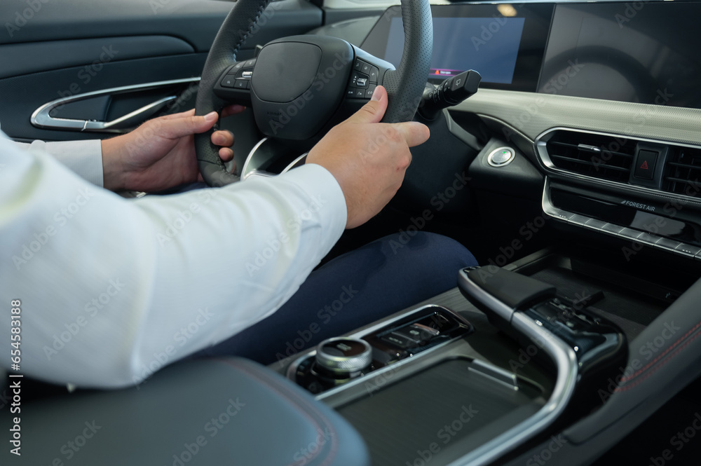 Close-up of a man's hands on the steering wheel of a modern car. 