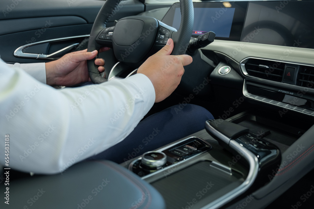Close-up of a man's hands on the steering wheel of a modern car. Close-up of a man's hands on the steering wheel of a modern car.