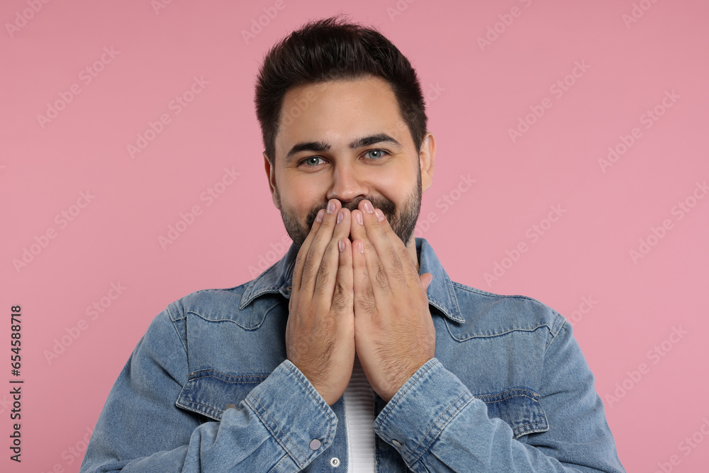 Embarrassed man covering mouth with hands on pink background Embarrassed man covering mouth with hands on pink background