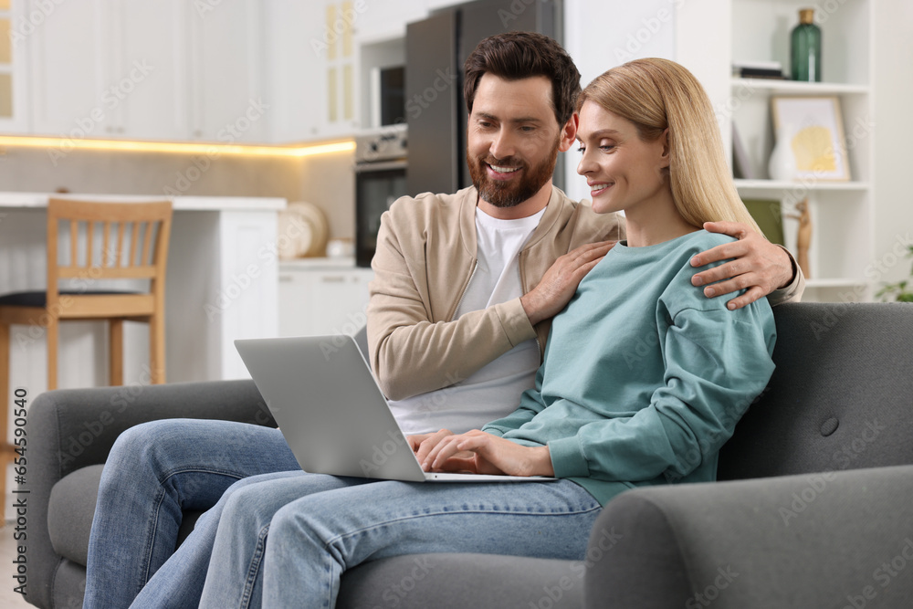 Happy couple with laptop on sofa at home Happy couple with laptop on sofa at home