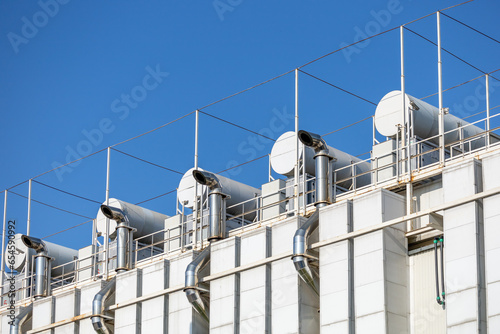 Ventilation pipes on the facade of computer data center. The fragment of the ventilation system against the blue sky. View from the street below