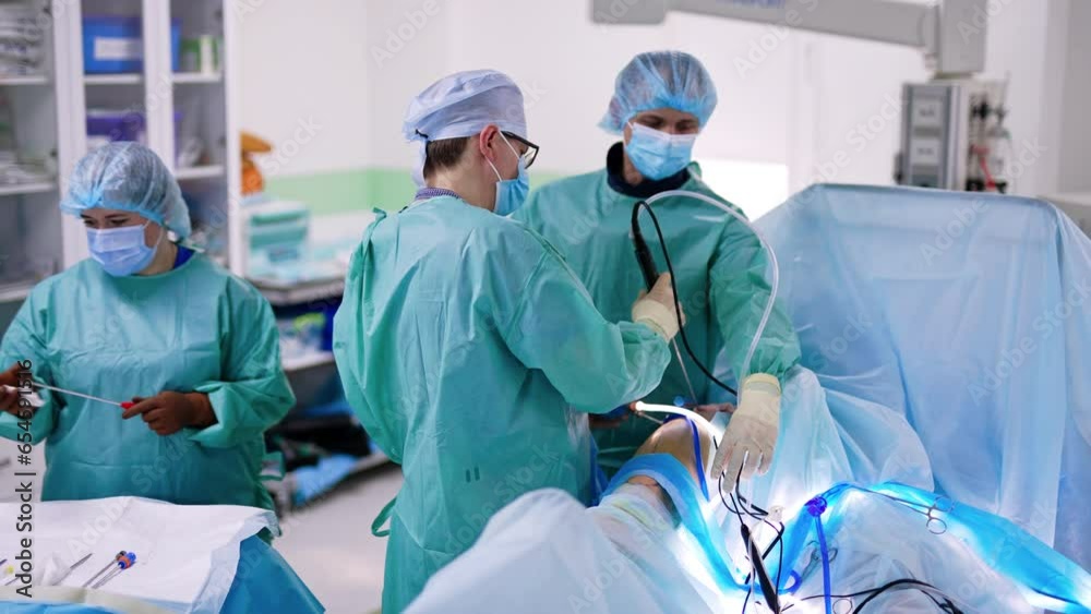Medical team working at operation uses advanced instruments and tools. Nurse arranges tools for the doctors. Medical team working at operation uses advanced instruments and tools. Nurse arranges tools for the doctors.