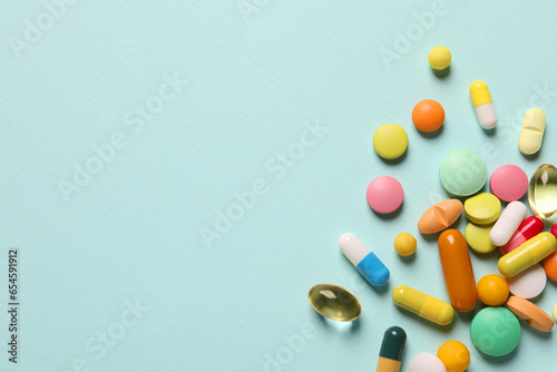 Schilderij op canvas Many different pills on light blue background, flat lay
