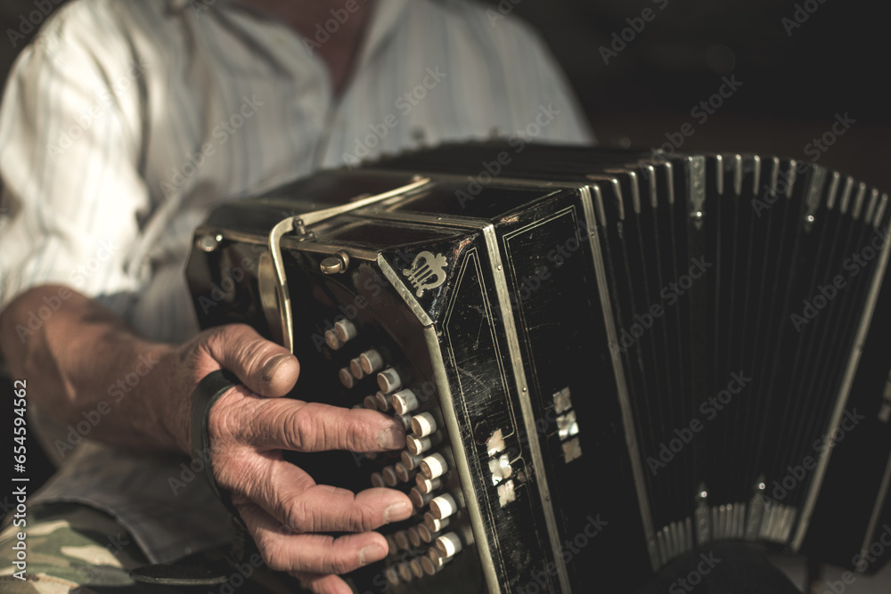 Aged male with white shirt and a wrinkled hand playing on bandoneon - obrazy, fototapety, plakaty 