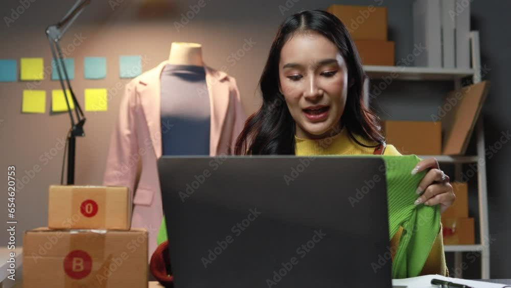 Employee of online clothing business sits in the office, checking orders and live selling on the platform, packing products according to orders and sending them to customers with the shipping company.
