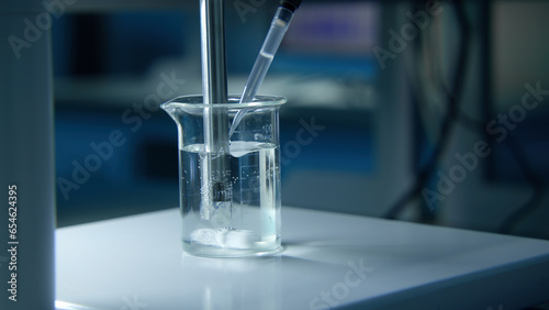 Rotating substance in glass of liquid in laboratory. Stock footage. Chemical experiment with substance and liquid in flask. Professional chemical experiment in laboratory