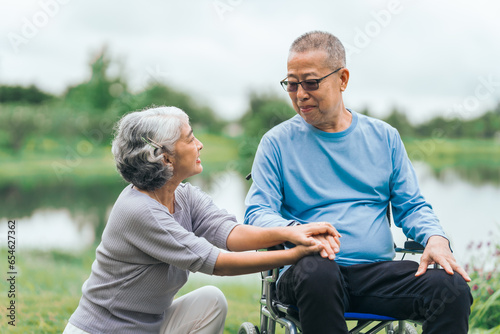 Asian people mature husband and wife, one in wheelchair, savoring peaceful outdoor moments in garden. Love and togetherness in midst of nature beauty. long live togetherness, valentine, insurance © M+Isolation+Photo