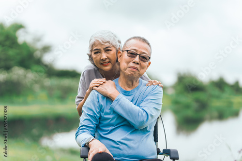 Asian people mature husband and wife, one in wheelchair, savoring peaceful outdoor moments in garden. Love and togetherness in midst of nature beauty. long live togetherness, valentine, insurance